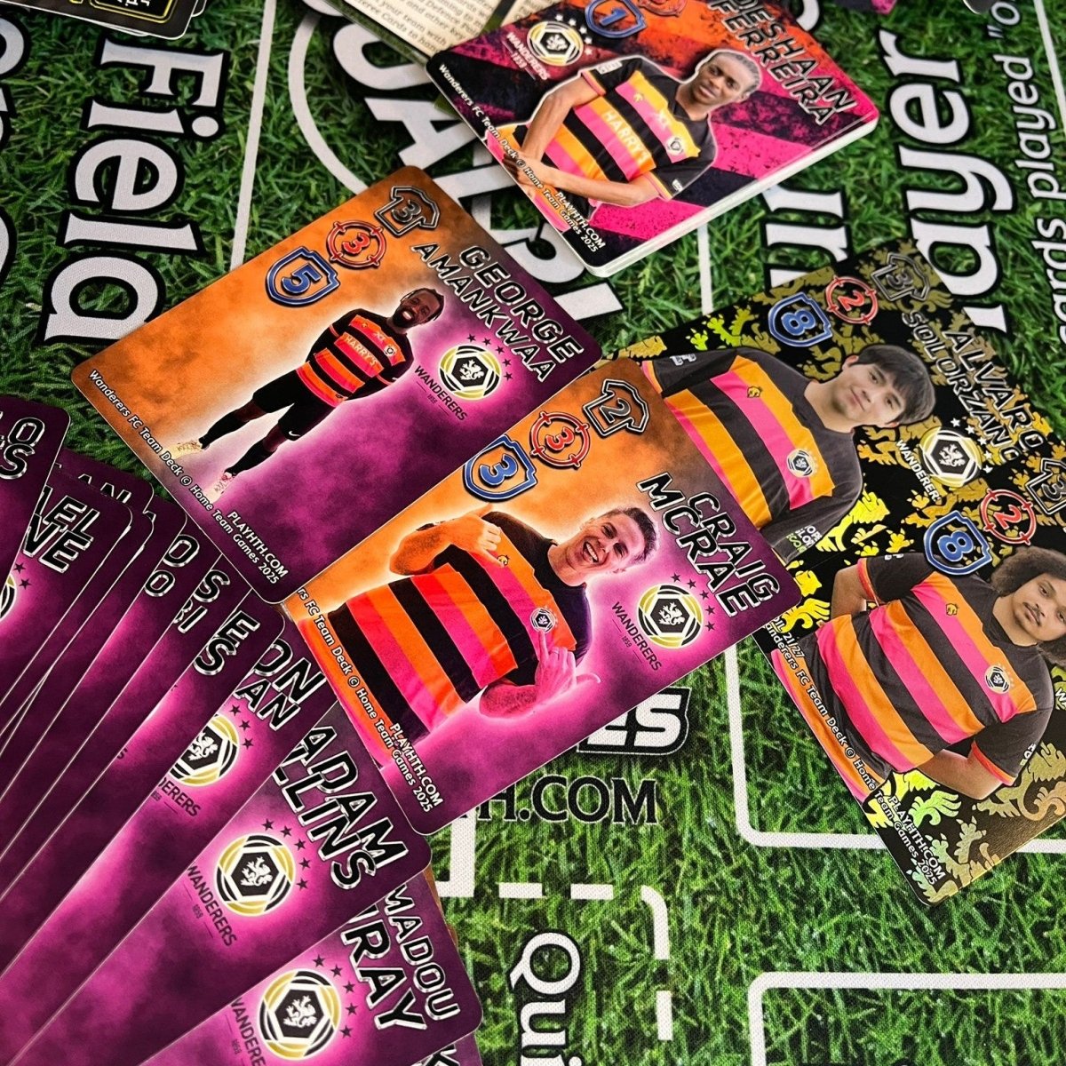 A selection of colourful Home Team Heroes Wanderers player cards displayed on a football-themed playmat, featuring players