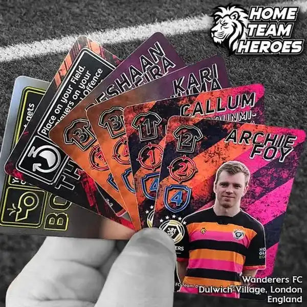 Hand holding Wanderers FC card deck with Archie Foy and colourful football cards on pitch background.